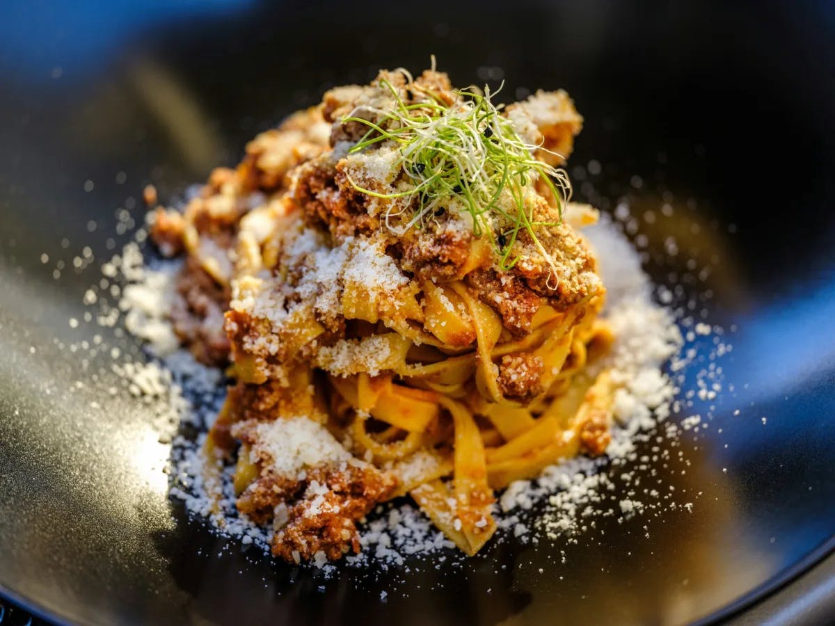 A gourmet pasta dish served on a black plate.