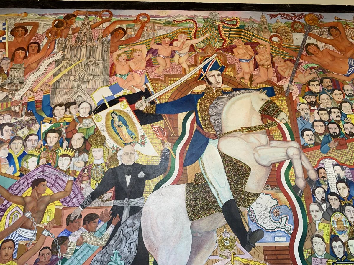 A colorful mural depicting a man on a horse with a sword and a sea of people around