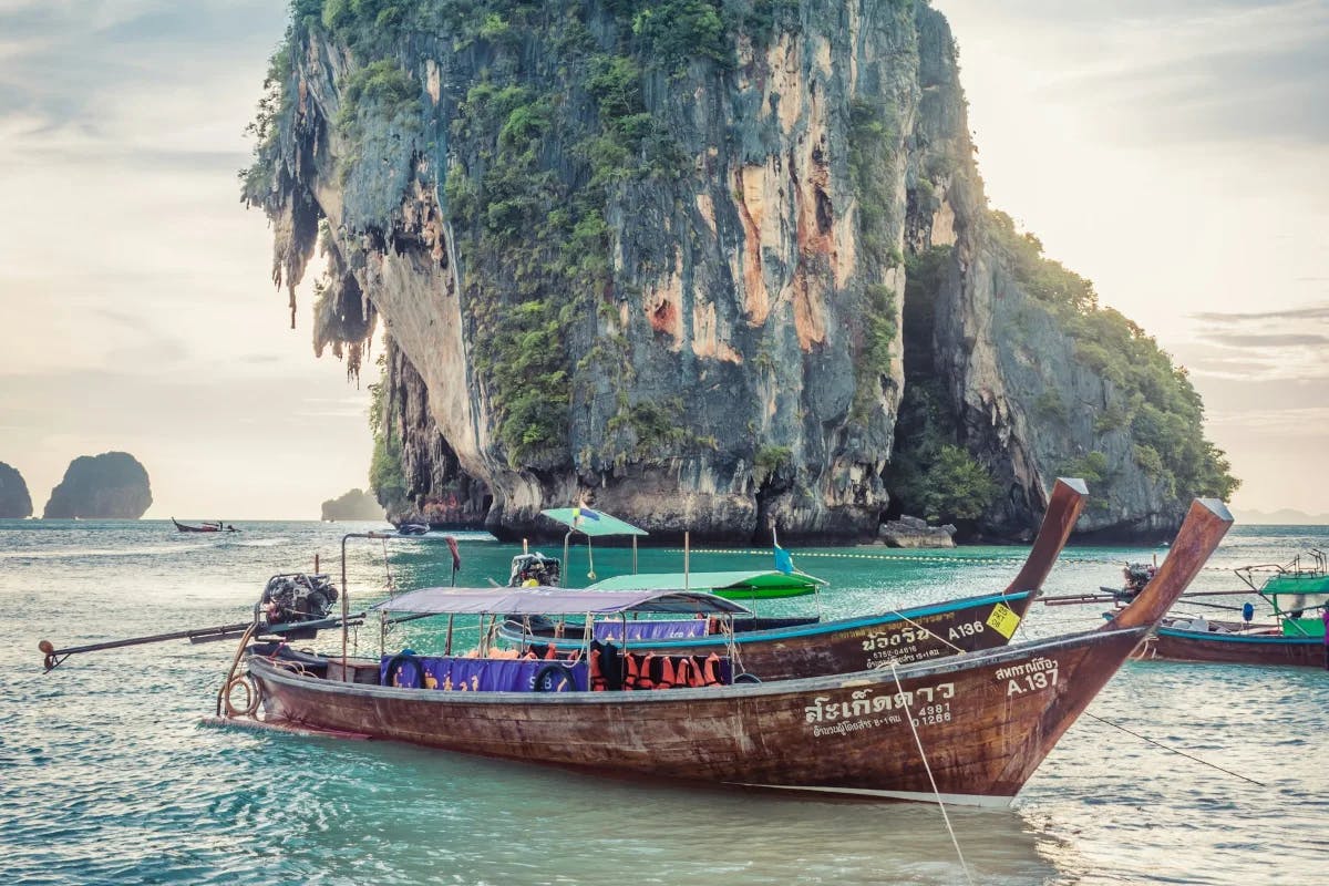 Boats at the sea near a large rock formation.