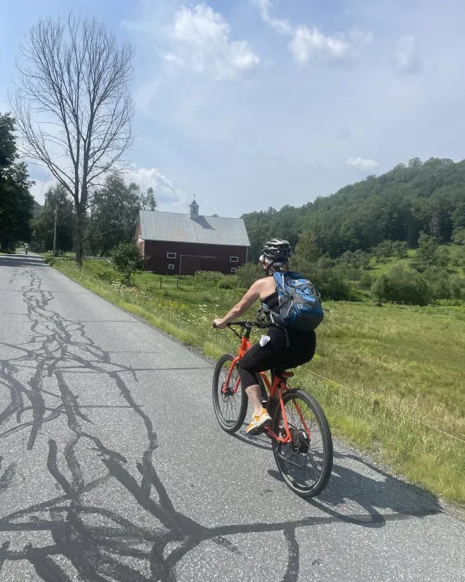 Advisor Kim Richter biking on the road along  green grounds