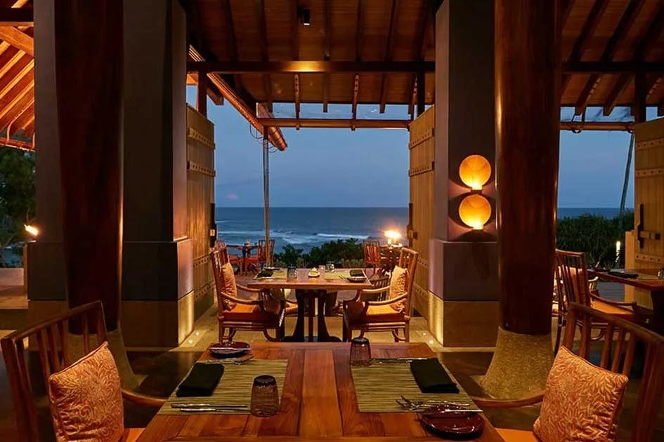 Luxury dining at a restaurant with wooden tables and warm lighting with a view of the Indian Ocean at Ocean Terrace at Cape Weligama.