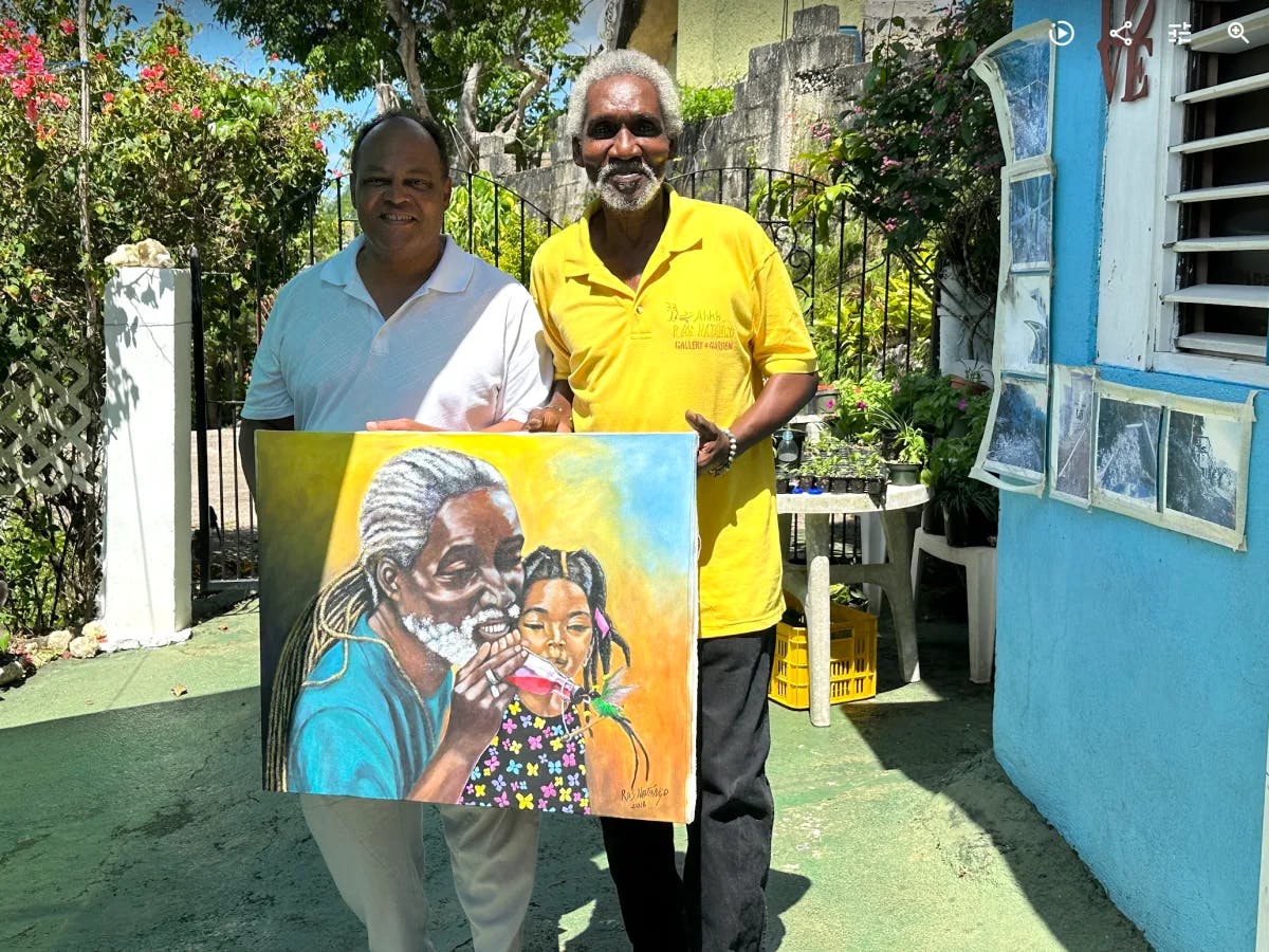 Two people stood outdoors holding a portrait painting during the daytime