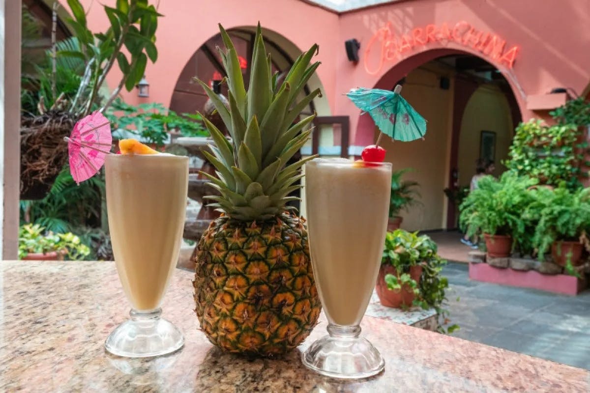 Two drinks on a table next to a pineapple