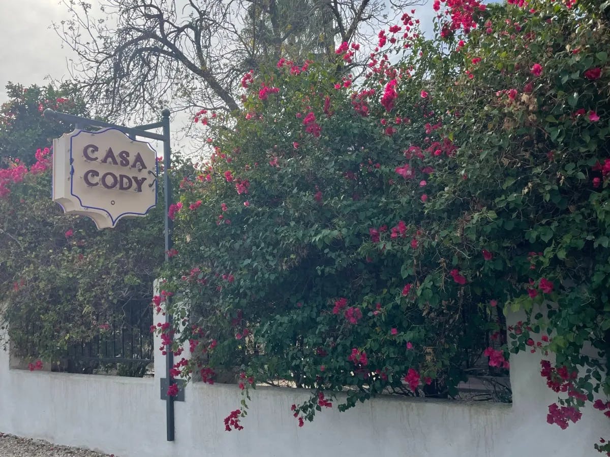 A hotel sign reading "Casa Cody" next to a flowery bush