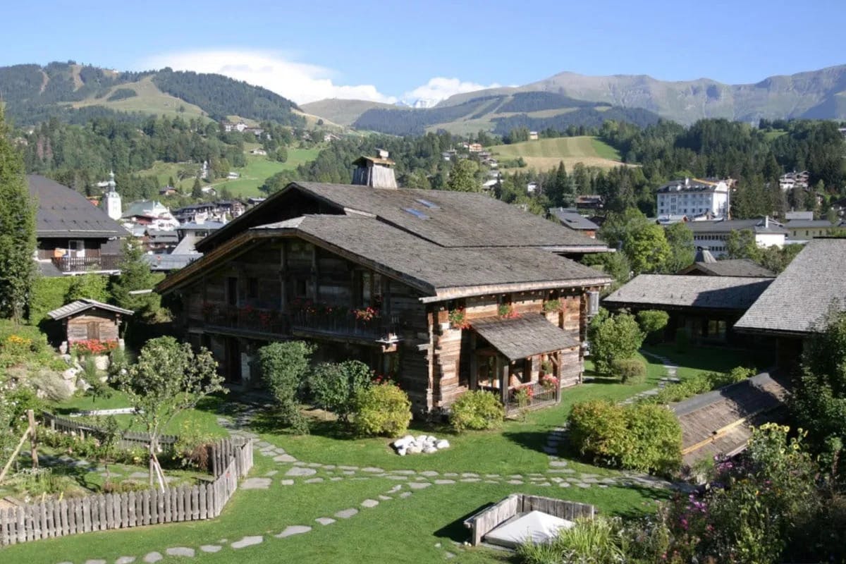 log cabin in an alpine village with mountains and blue sky behind