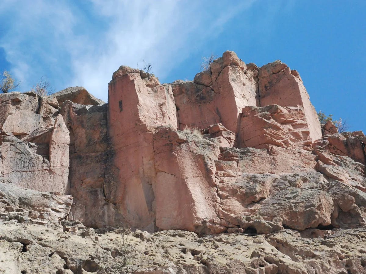 A majestic pinkish rock formation rises under a clear sky.