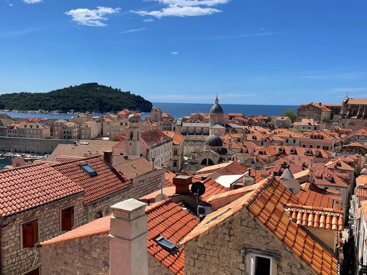 An aerial view of Dubrovnik with red roofed buildings and the ocean in the distance