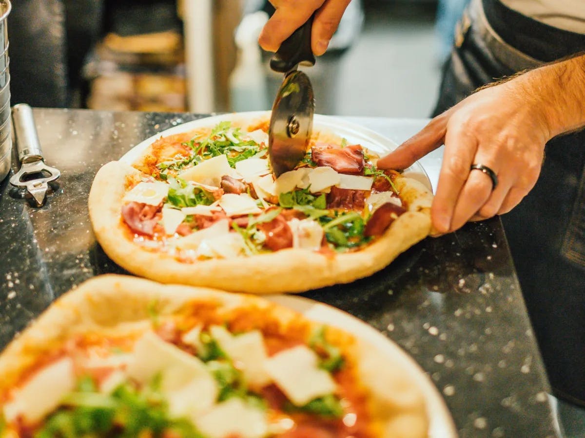 A person cutting pizza. 