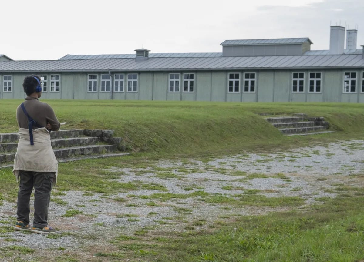 A person wearing blue head phones and looking at a long grey building. 