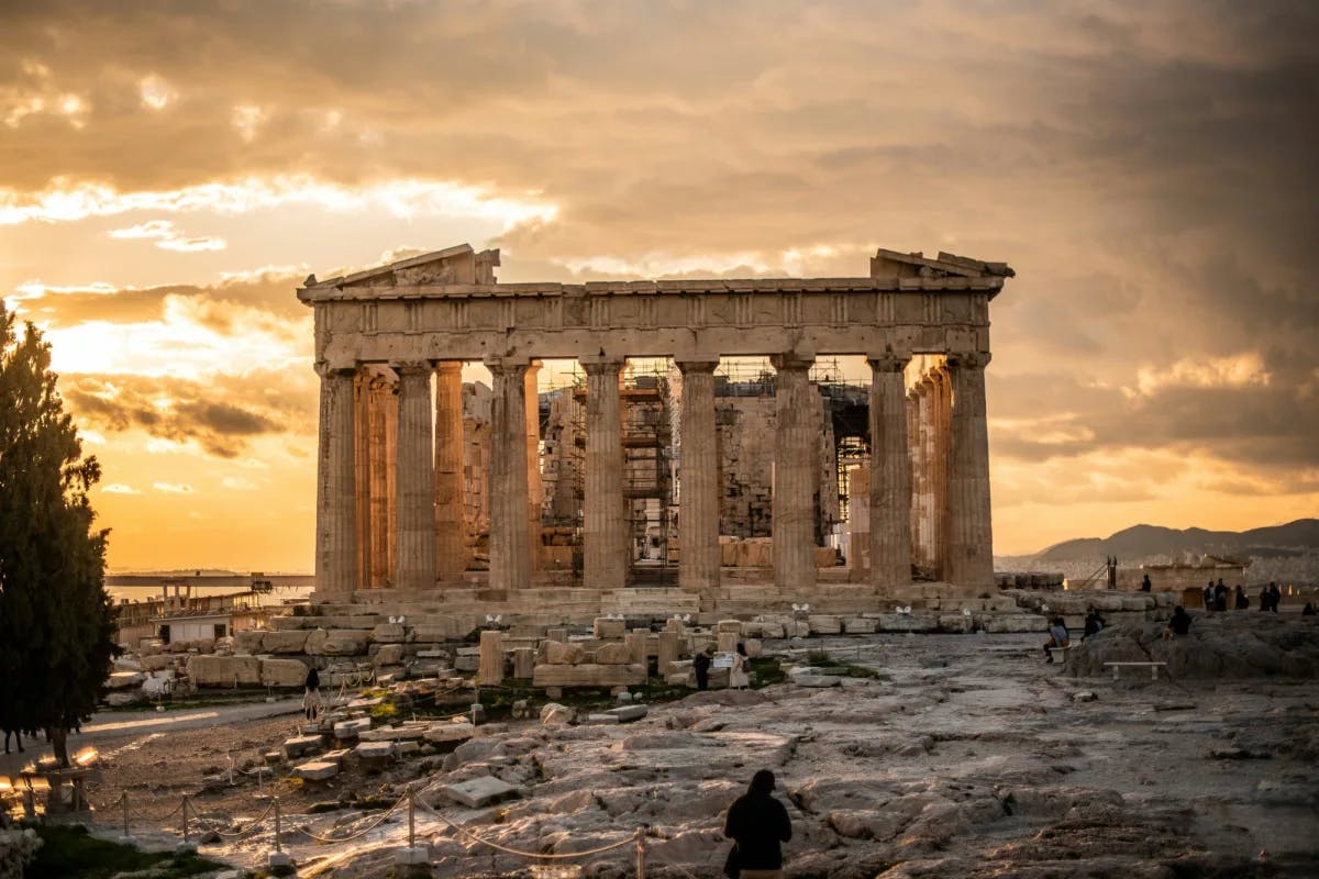 Ancient greek ruins with a cloudy sunset above.