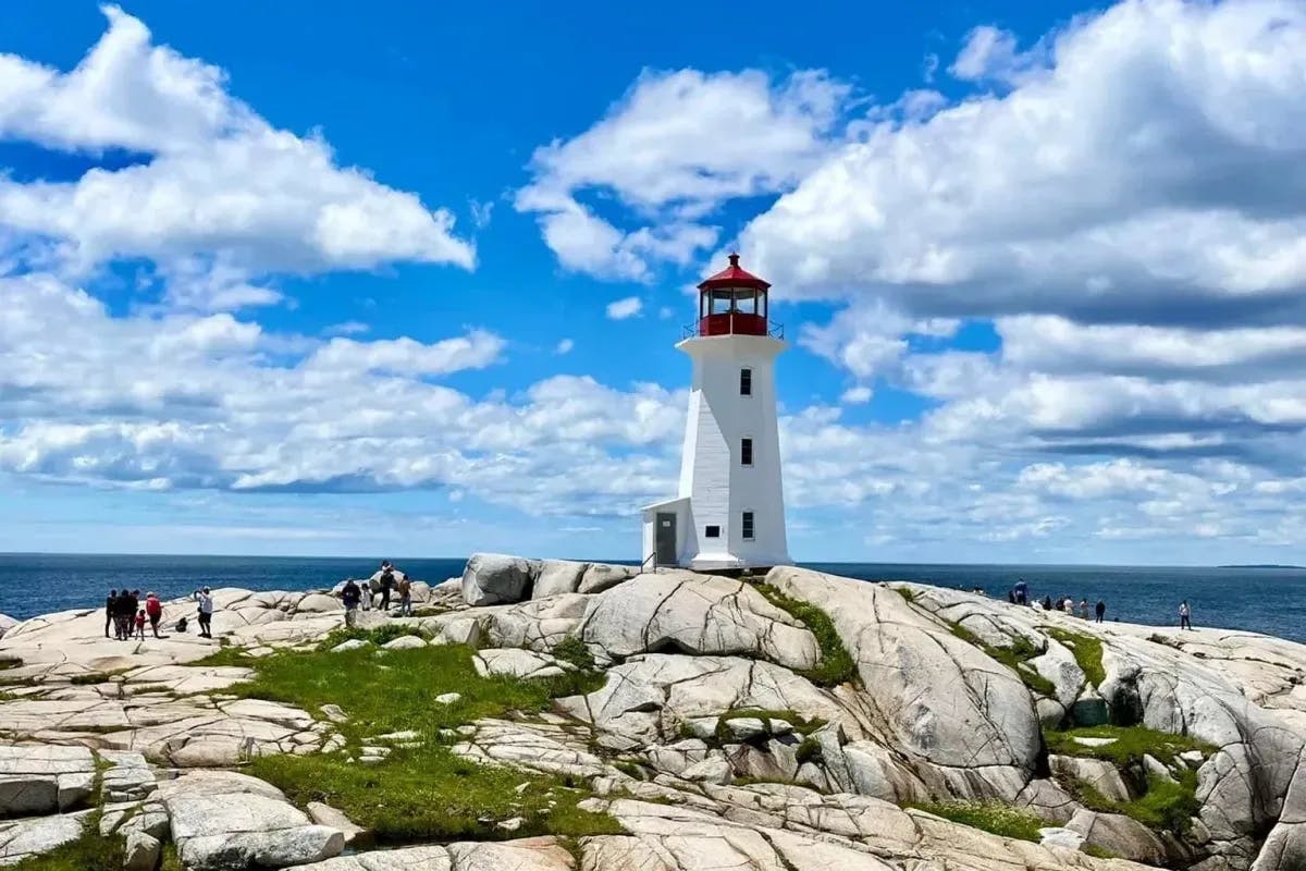 A lighthouse at Peggy's Cove on a rocky outcropping on a sunny day.