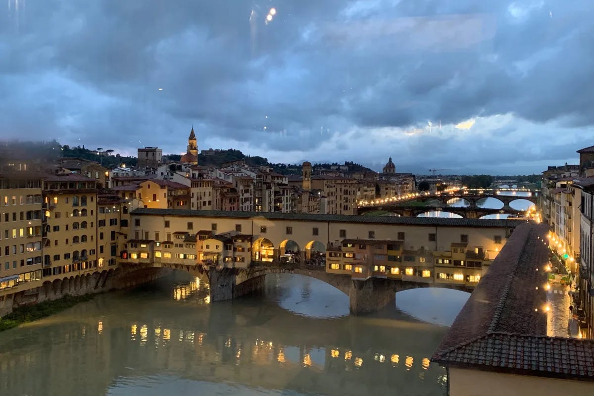 An aerial view of the Ponte Vecchio with bridges connecting the buildings over the water running through the city.