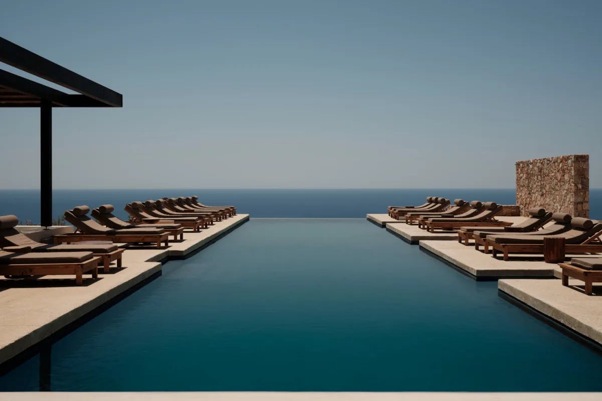 an infinity pool surrounded by loungers overlooking the sea