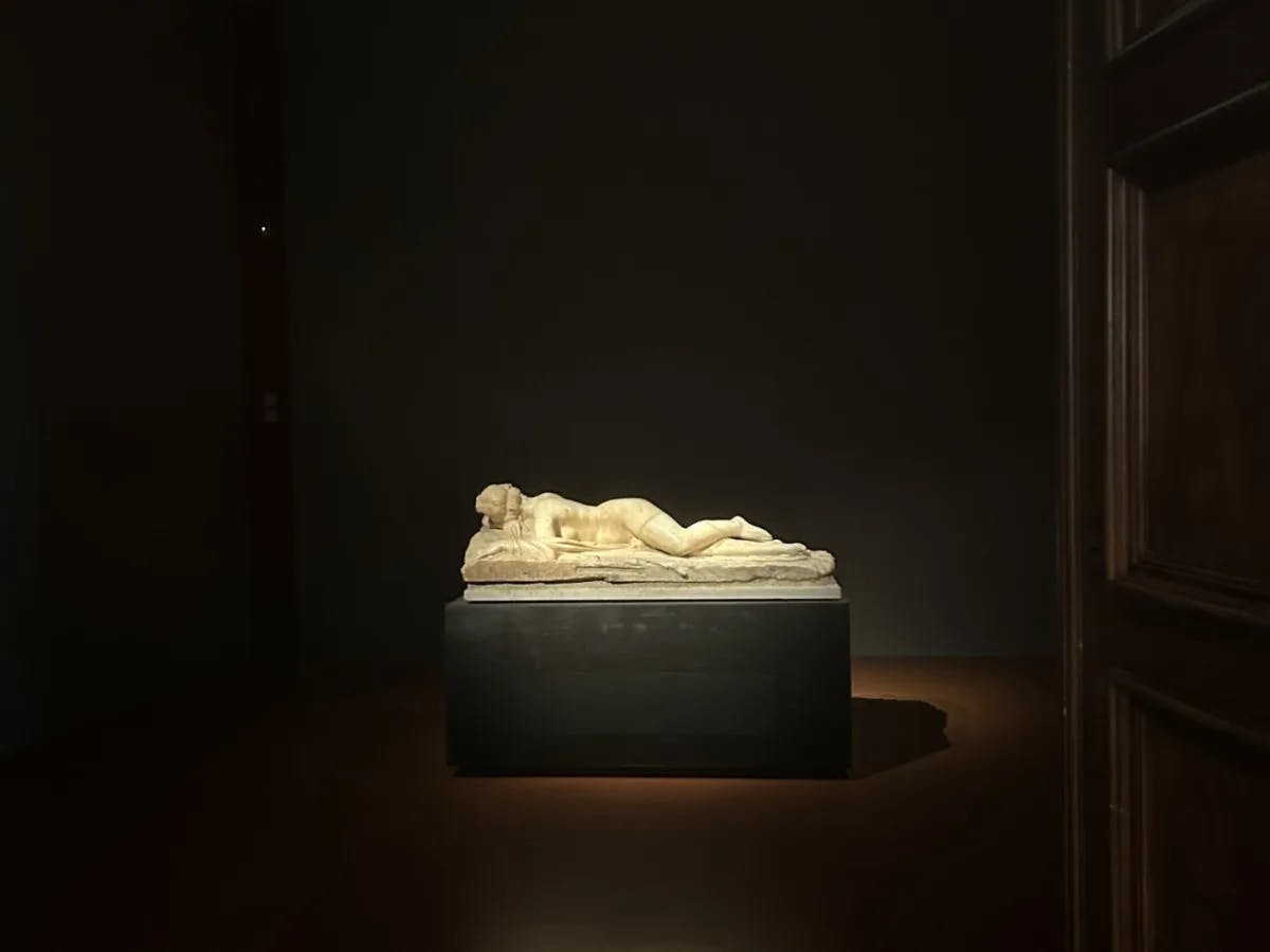 A statue of a woman laying on a bed in a museum