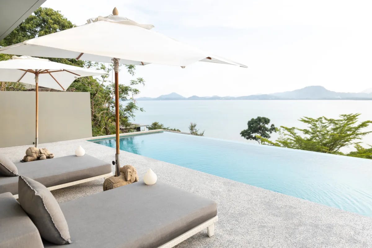 a balcony with a sleek infinity pool and plush grey loungers overlooking the ocean