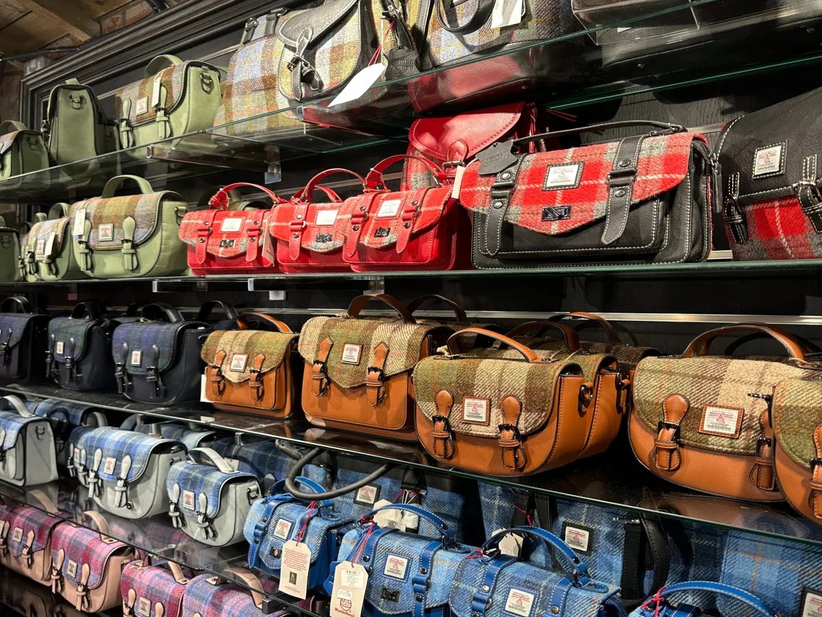 The image displays a colorful array of handbags neatly arranged on shelves, showcasing a variety of designs and patterns.