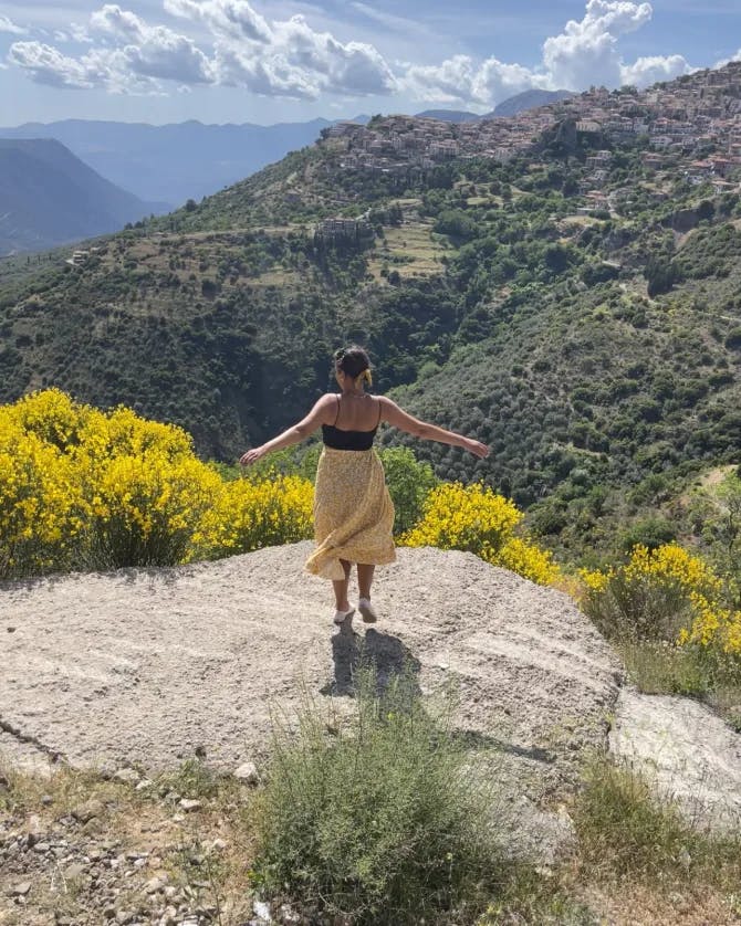 Travel advisor standing on a hill covered in yellow wildflowers overlooking a lush canyon.