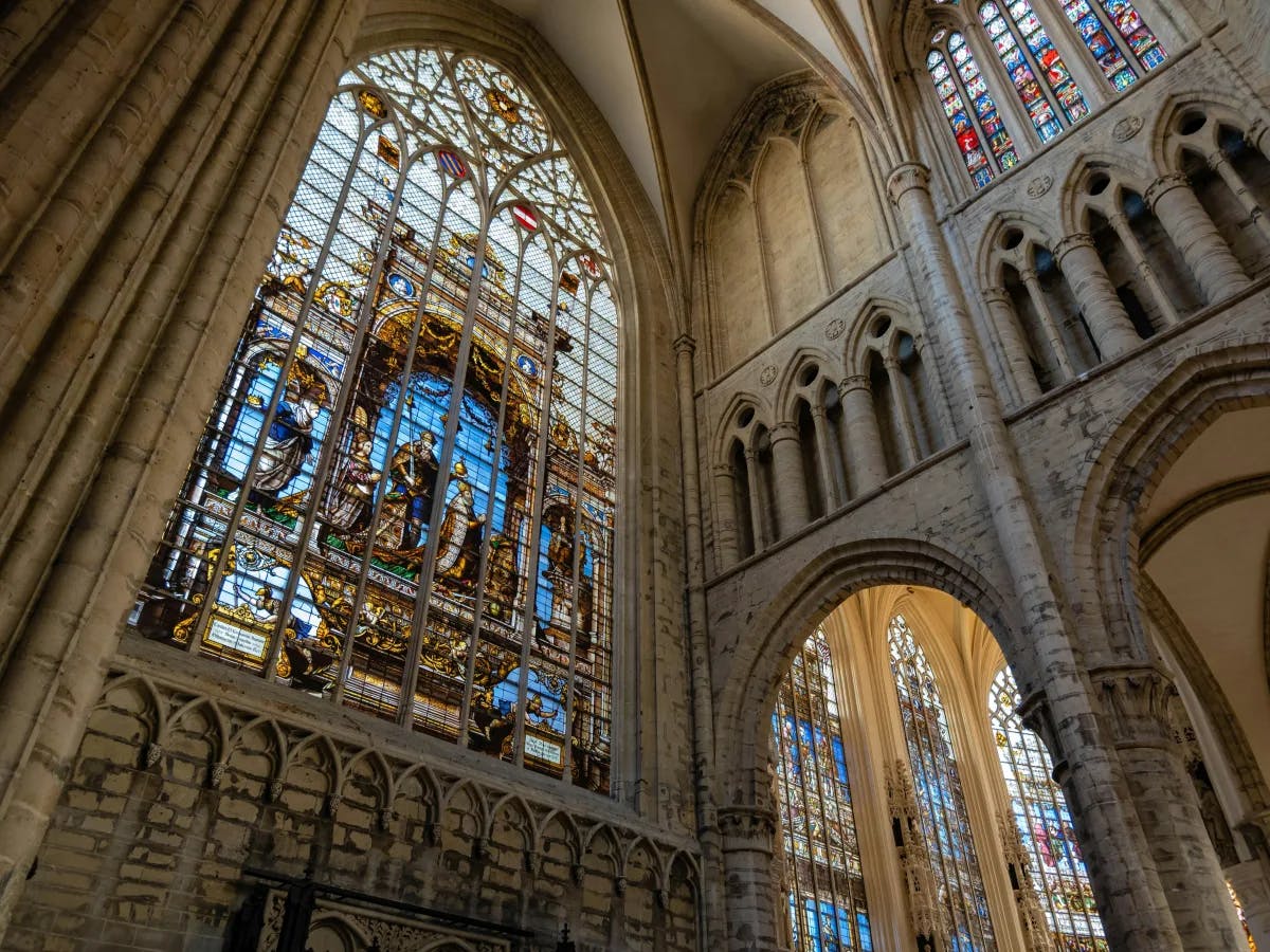 An interior of a cathedral with various arched and stained glass windows. 