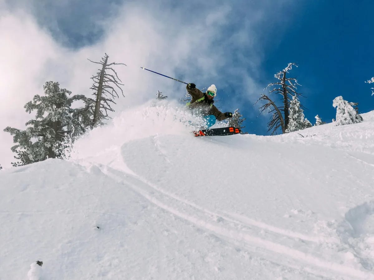 A view of someone turning with their skis and gear on surrounded by powdery snow and pine trees.