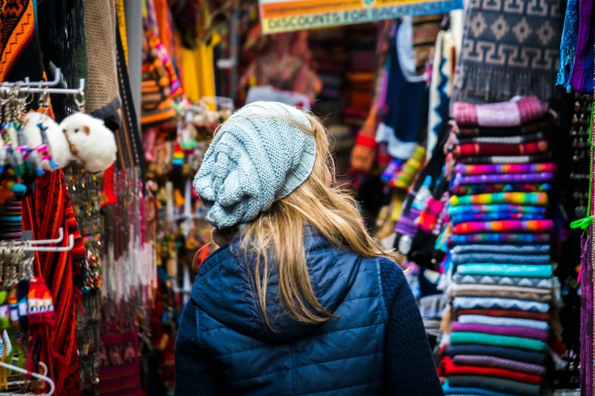 A women walking through a market with fabrics and souvenirs either side