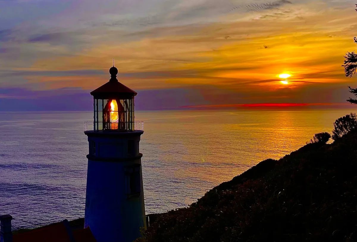 A lighthouse near ocean during sunset.