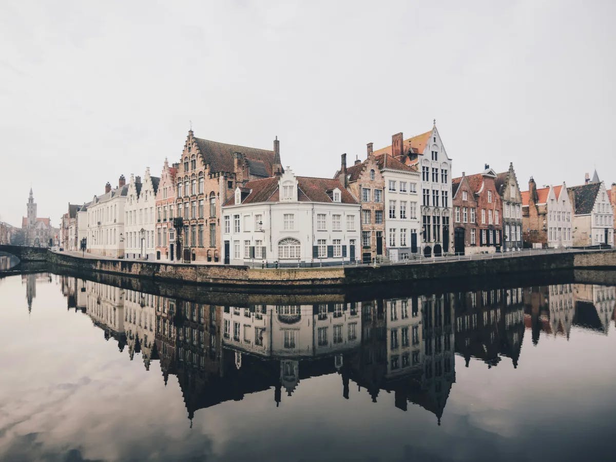 View of pretty white and beige buildings along a calm waterfront in Bruges, Belgium