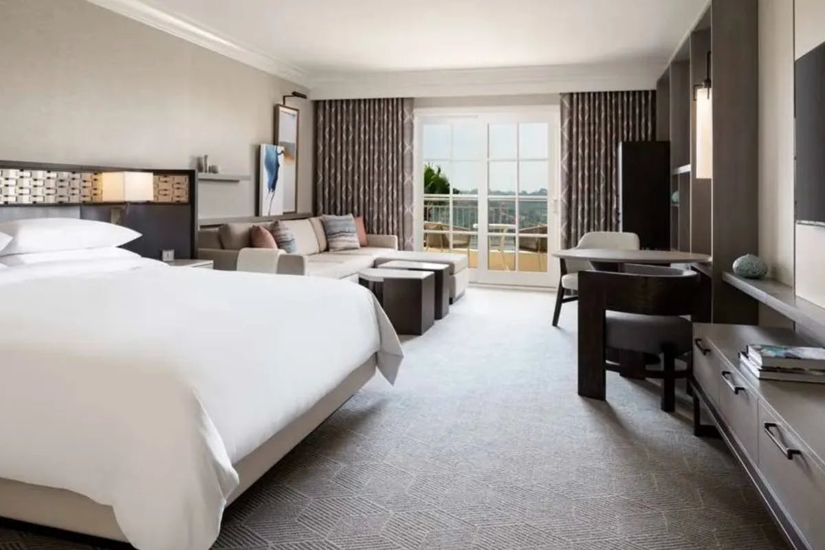 hotel room with gray walls and a balcony and a white bed