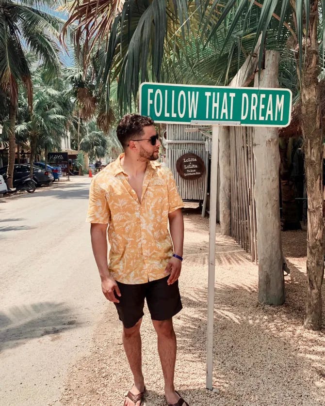 A man standing near a board saying Follow that Dream. 