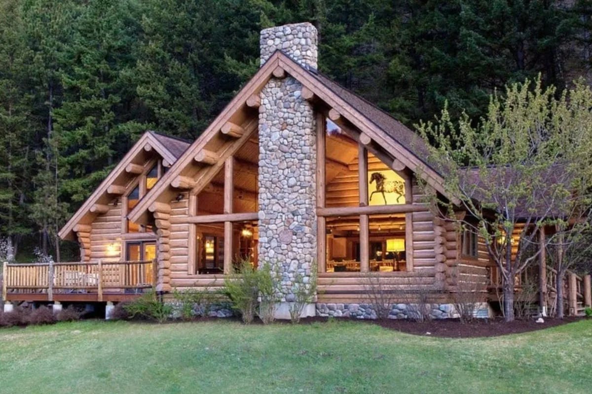 log cabin exterior with tall stone chimney surrounded by forest