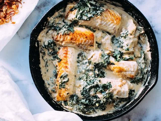 An aerial view of a salmon stew served in a black bowl at a restaurant.