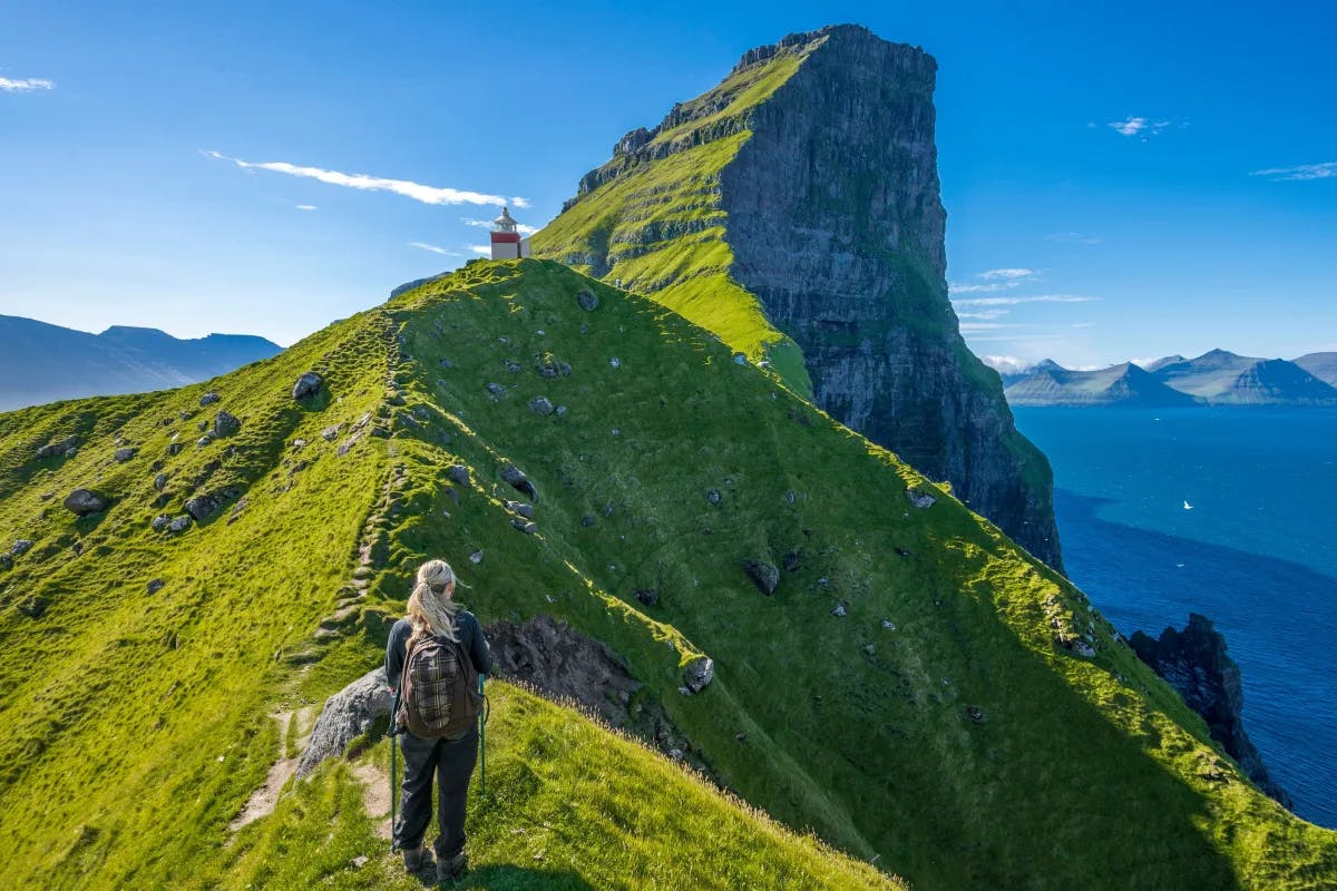 A person walking along a hiking path across a mountainous island during the daytime