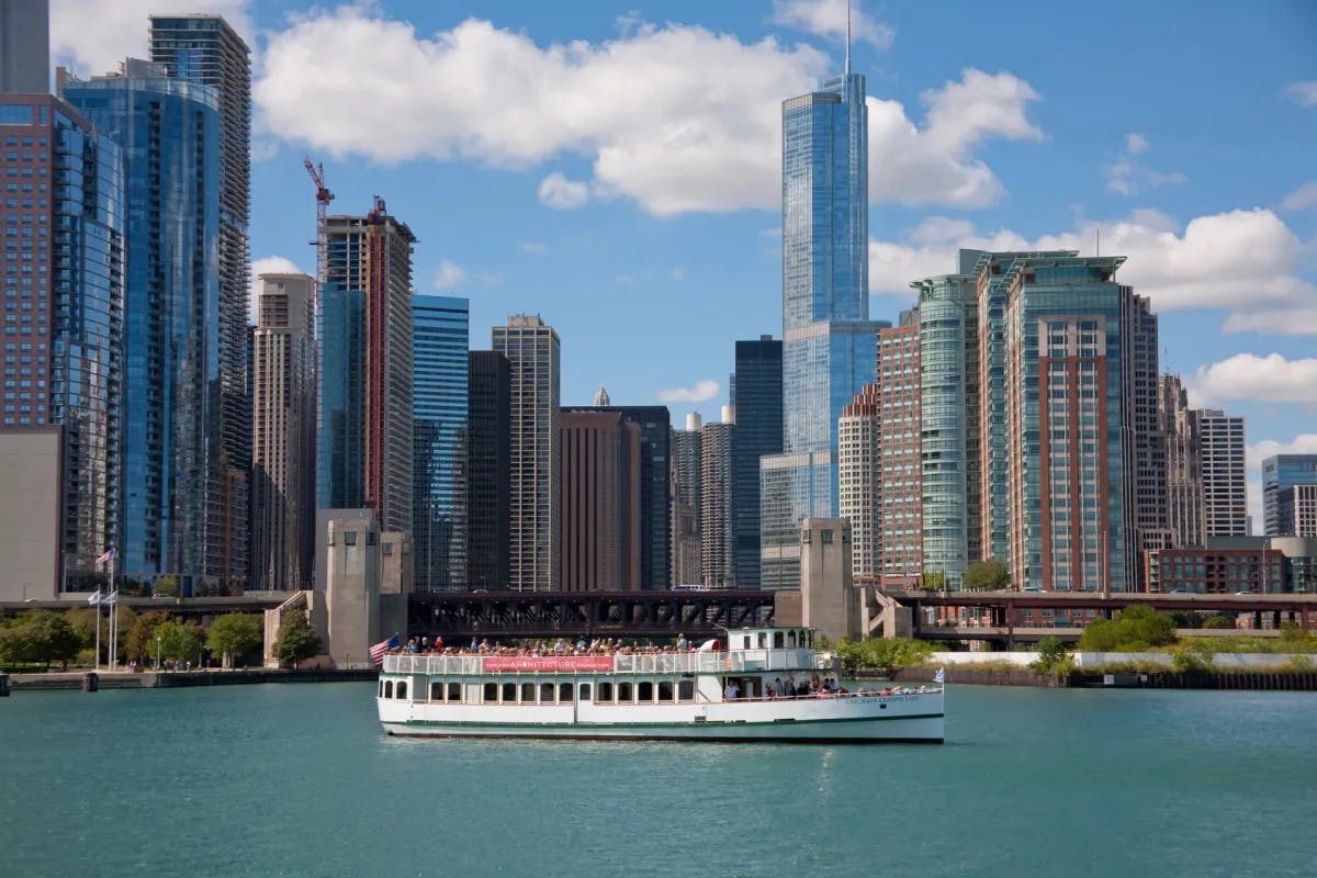 A view of a river cruise boat on the Chicago river with skyscrapers in the background. 