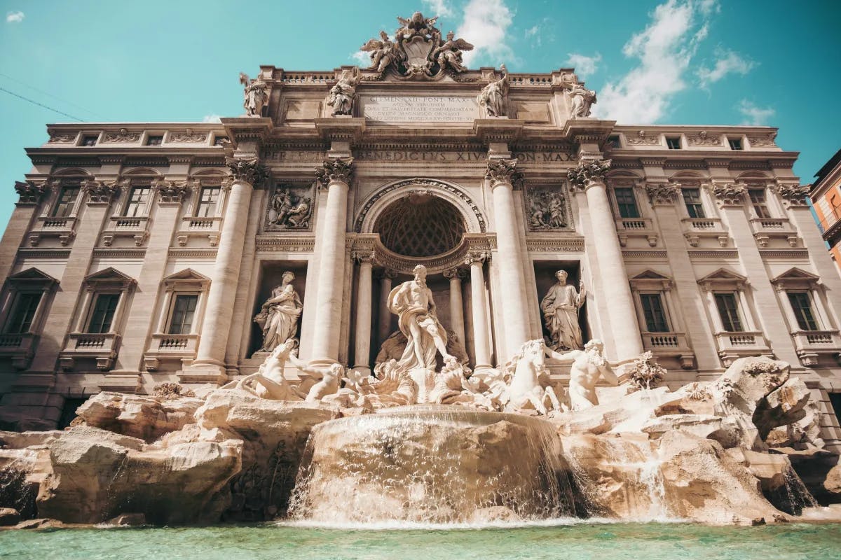 A front view of the Trevi Fountain and grand building behind in Rome.