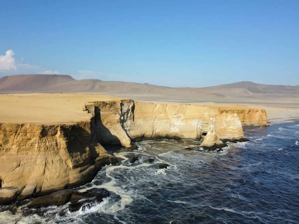 A serene coastal cliffside offers a breathtaking view of the expansive ocean under the azure sky.