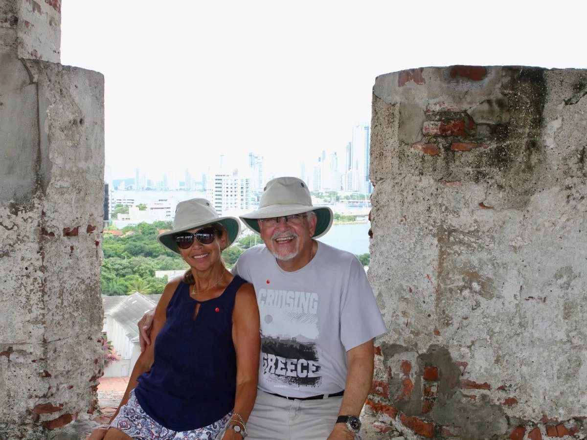 Two contemplative figures rest amid aged walls, gazing over an urban skyline.