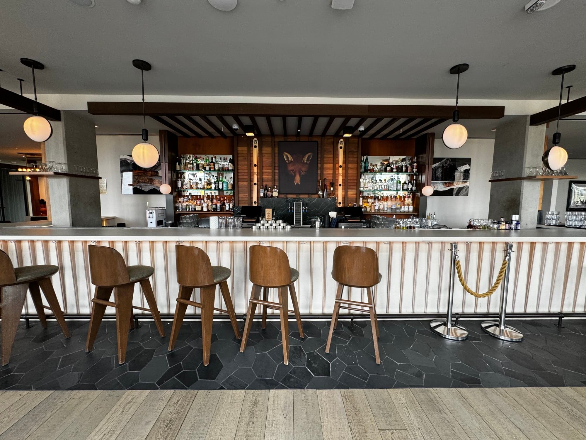 Sleek bar seating and counter under hanging lights. 