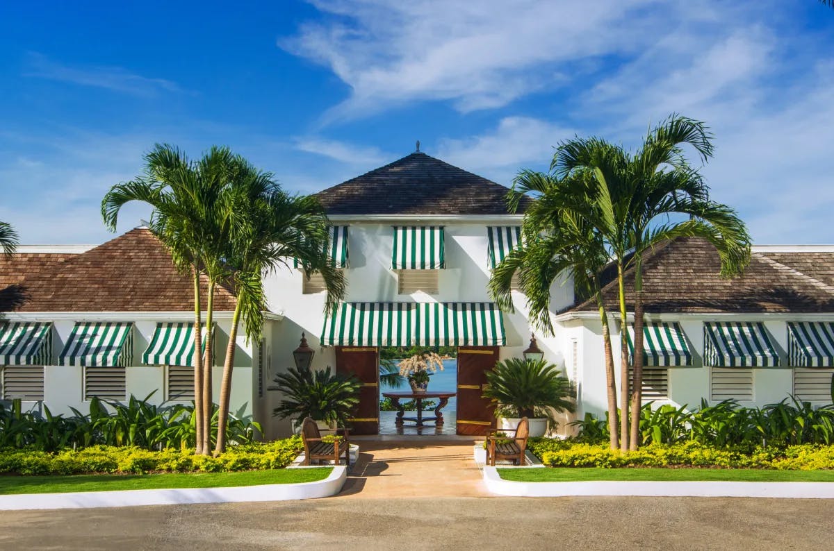 a white beachfront hotel with green-and-white striped awning