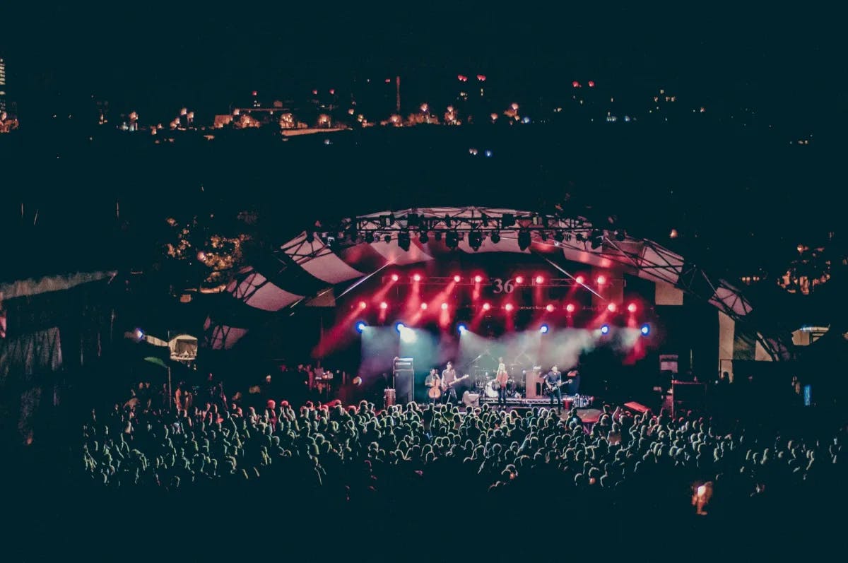 A large concert venue filled with people and with red lights strobing.