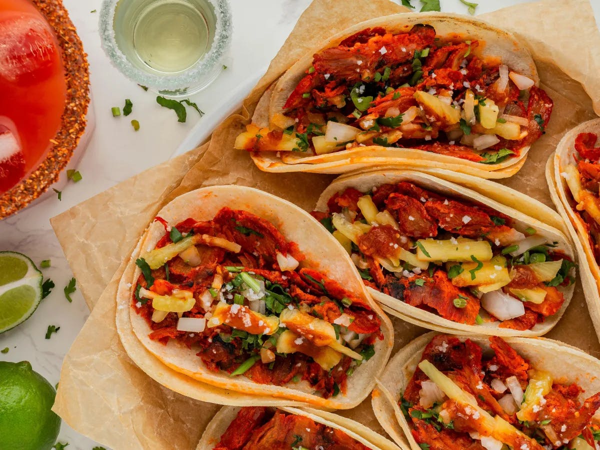 A delectable spread of tacos with fresh toppings, lime wedges and drinks.