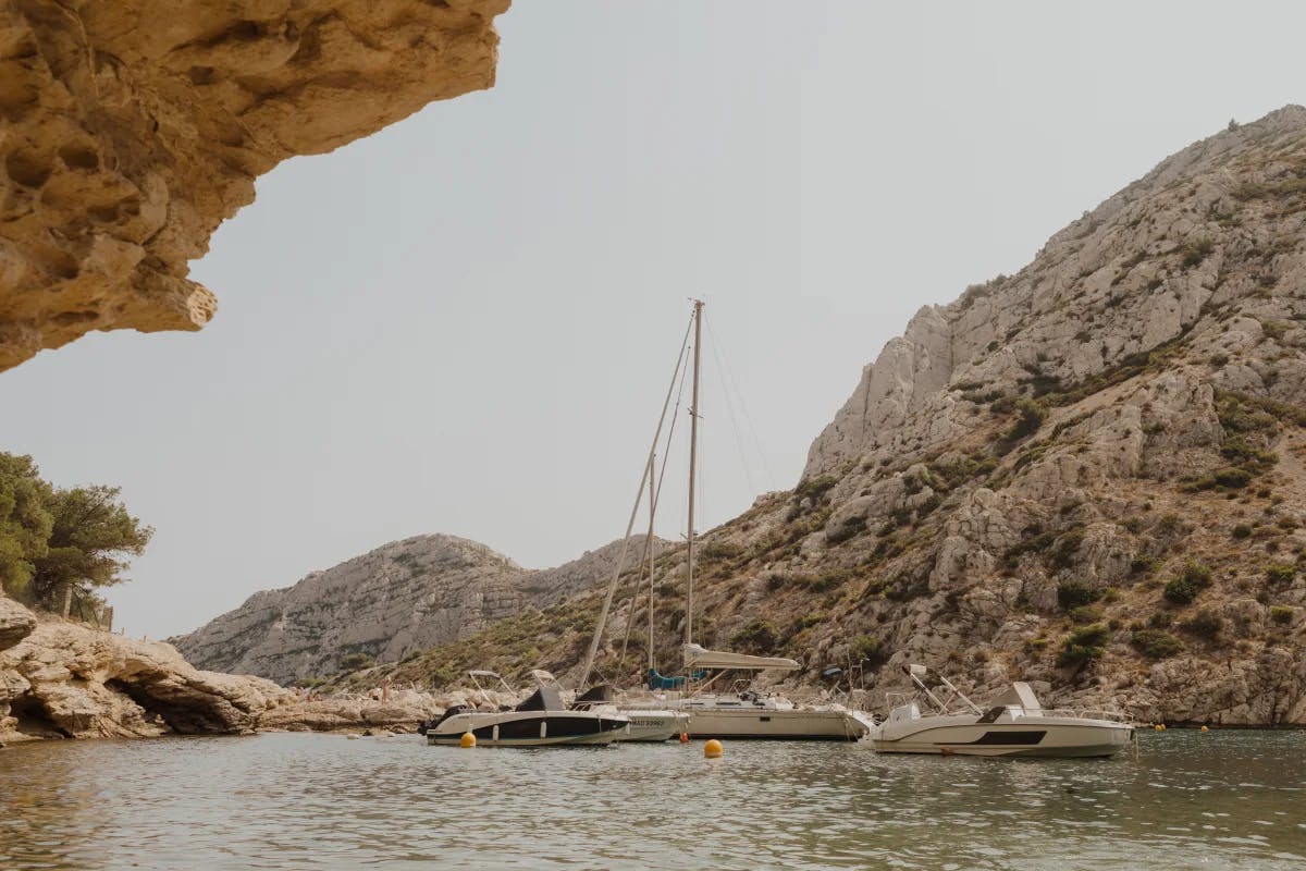 Three boats in the water by a cliffside during the daytime