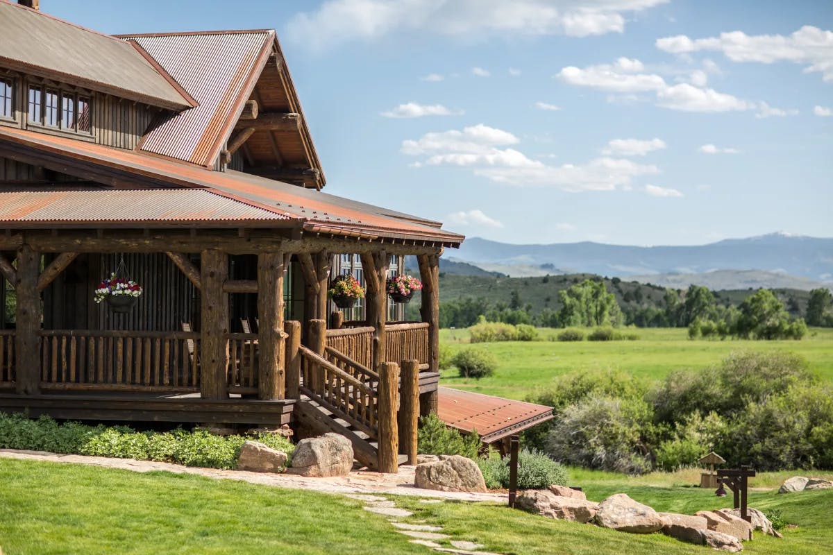 The exterior of Brush Creek Ranch showing a large cabin in the picturesque countryside.