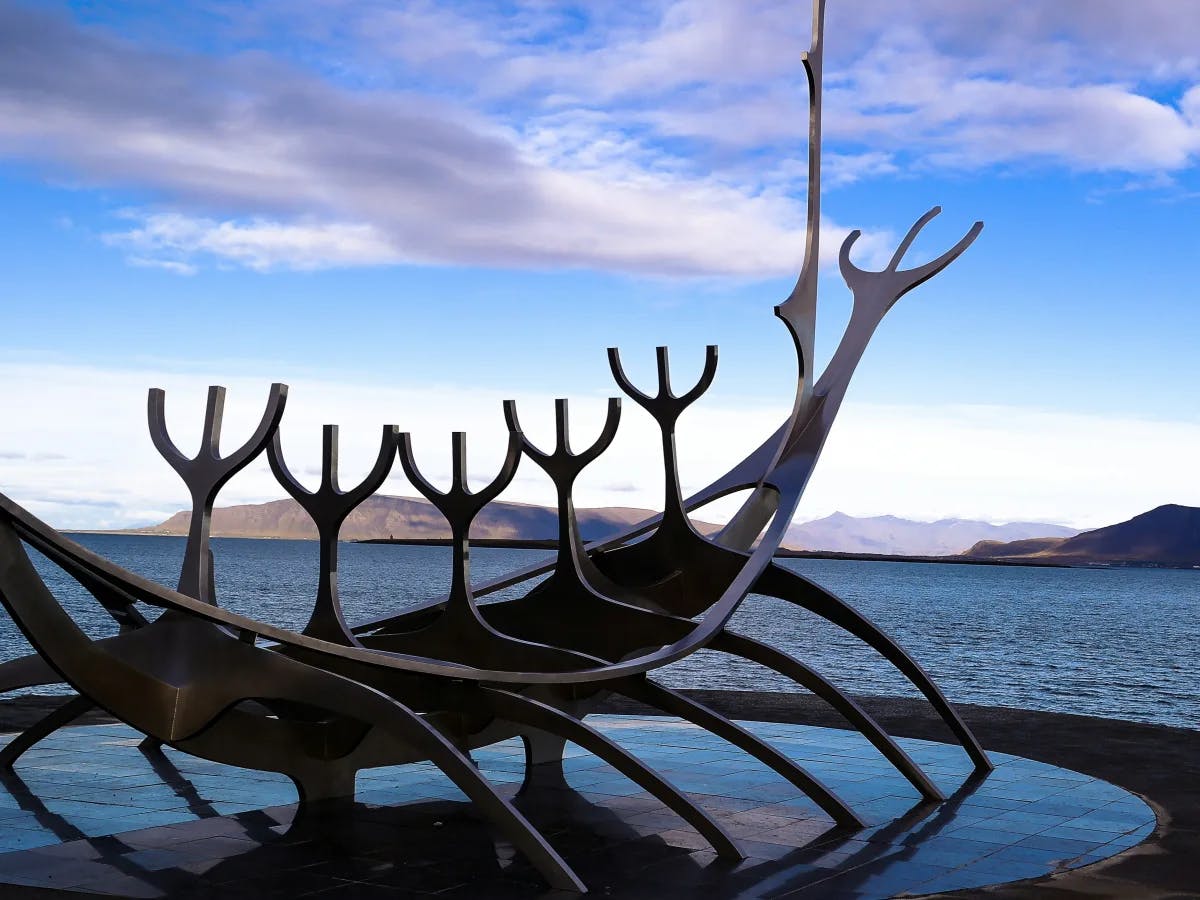 A majestic whale sculpture stands proudly against clear blue skies and distant mountains.