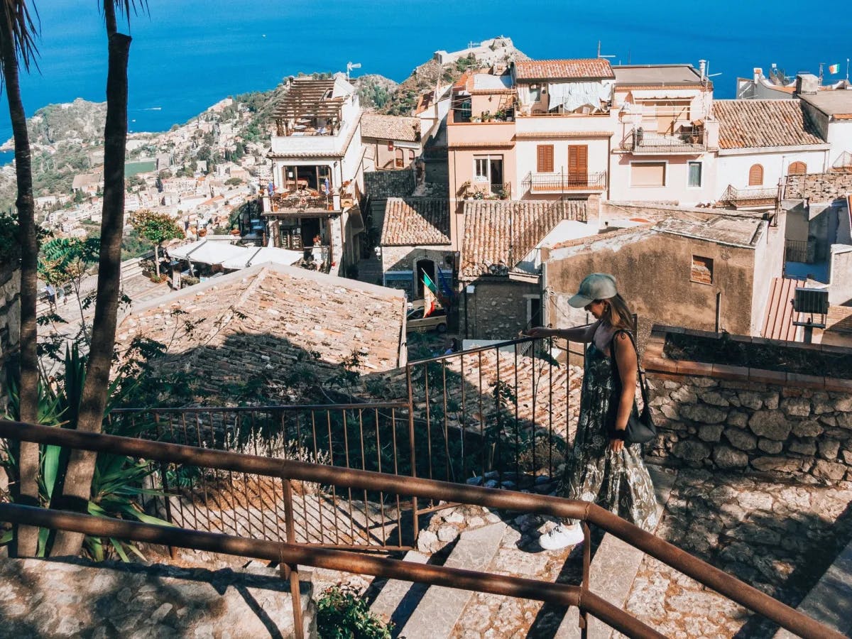 A man walking the stairs with town buildings and the ocean in the background.