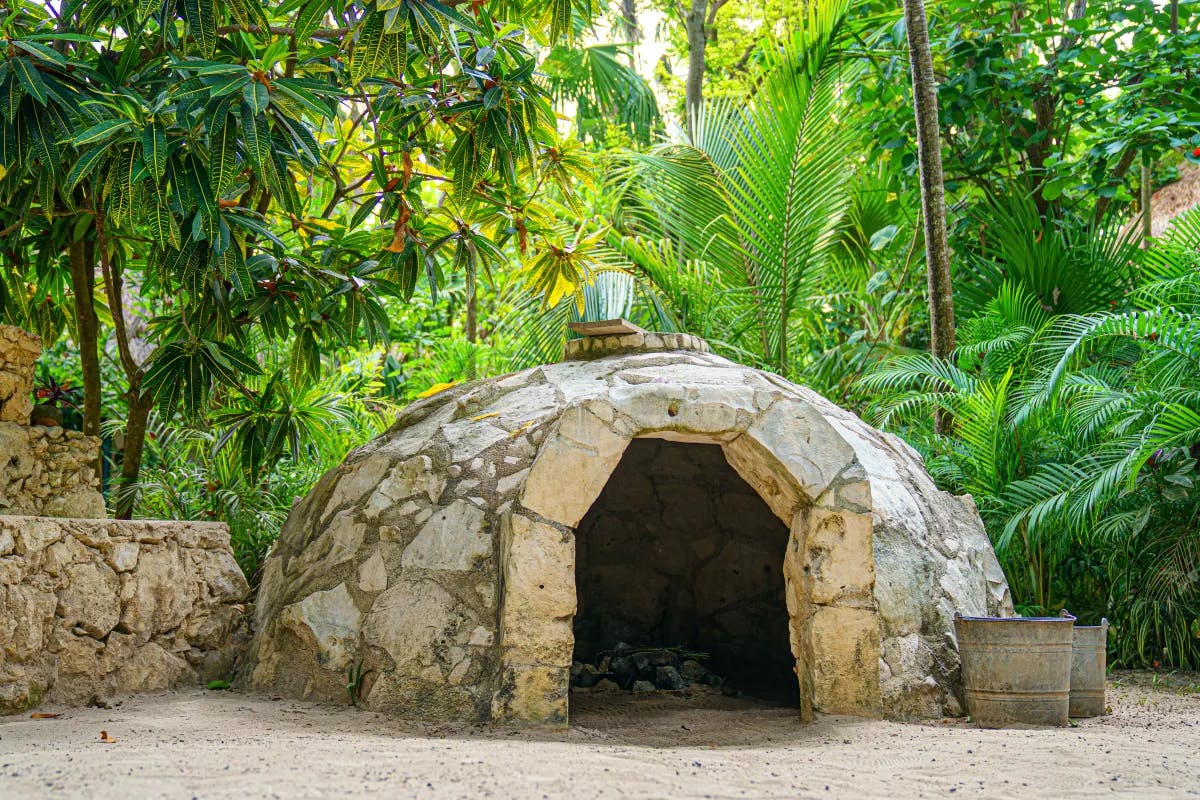 A temazcal, a rock sweat lodge, surrounded by trees in Maya Riviera Mexico.