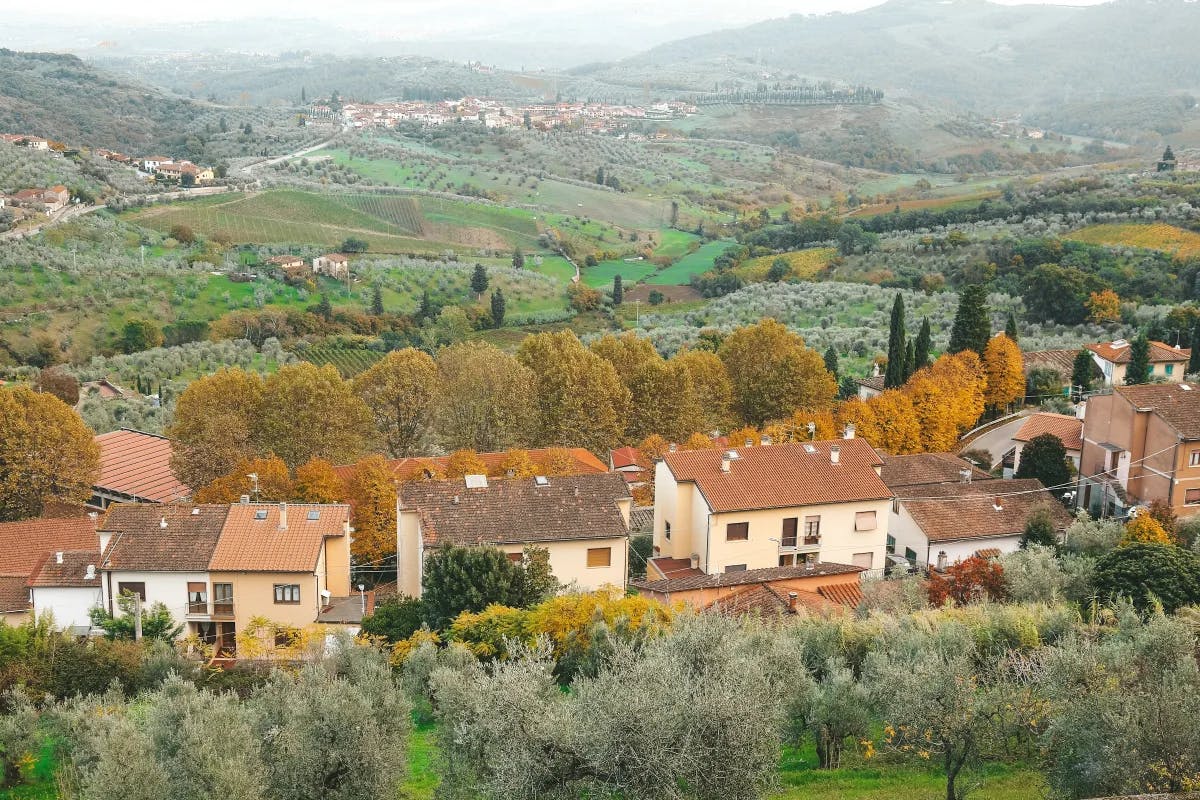 Rolling hills and red-roofed buildings in the Tuscan countryside.