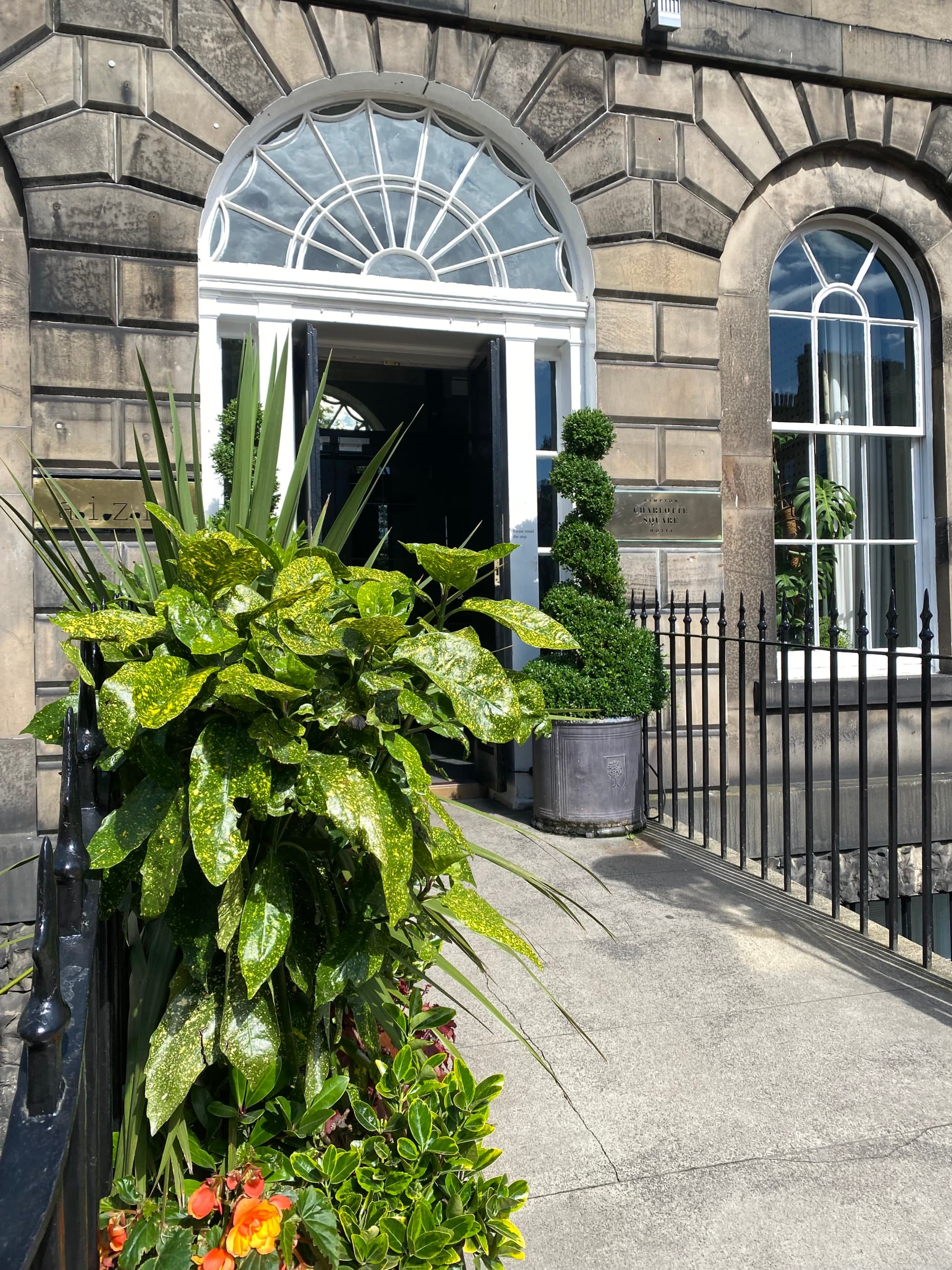 Hotel entrance with stone walls and large tropical plants.