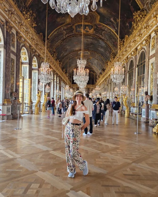 Picture of Alexandria at Palace of Versailles in front of chandeliers in a grand hallway