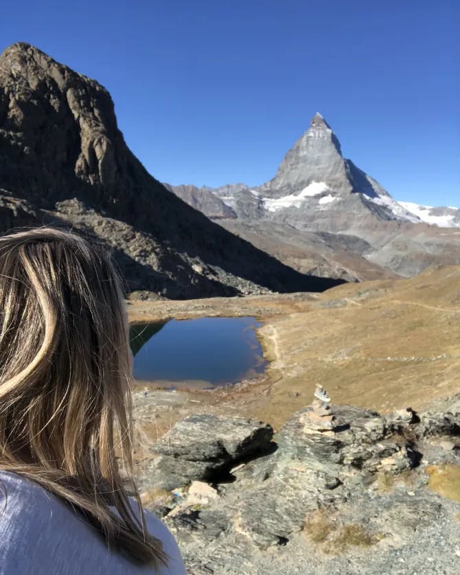 Travel advisor Amy looking at a view of Riffelsee lake with snow-capped mountains behind