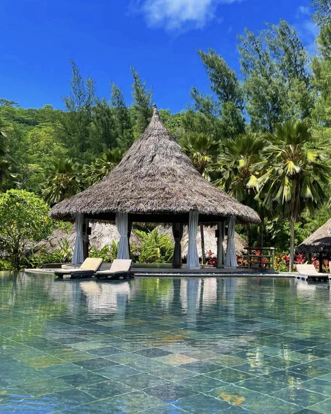 View of hotel pool and lounge chairs in the Seychelles on a sunny day