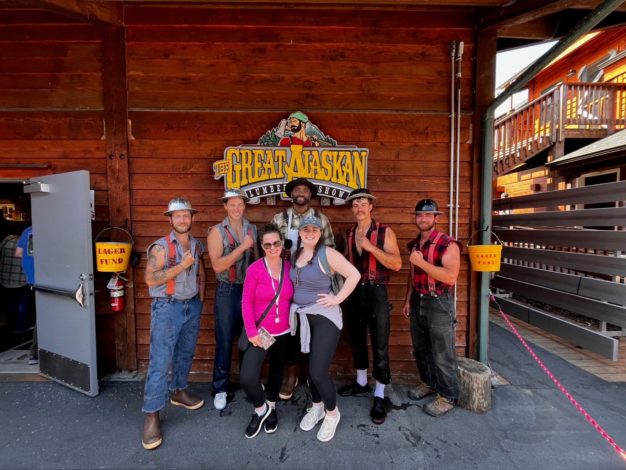 Advisor posing outside the Lumberjack Show with performers on a sunny day.  